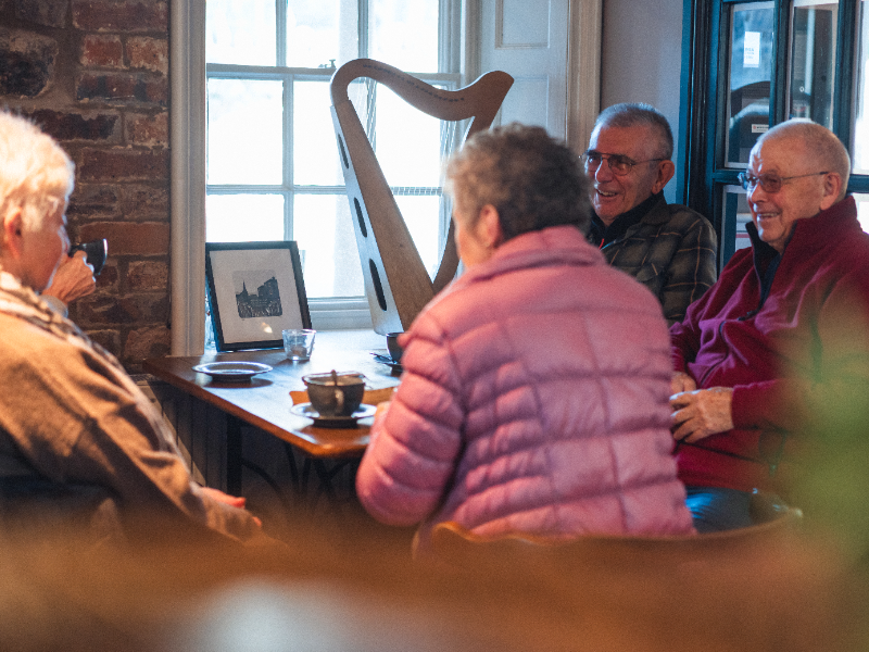 Older people sitting around a table with a coffee, chatting